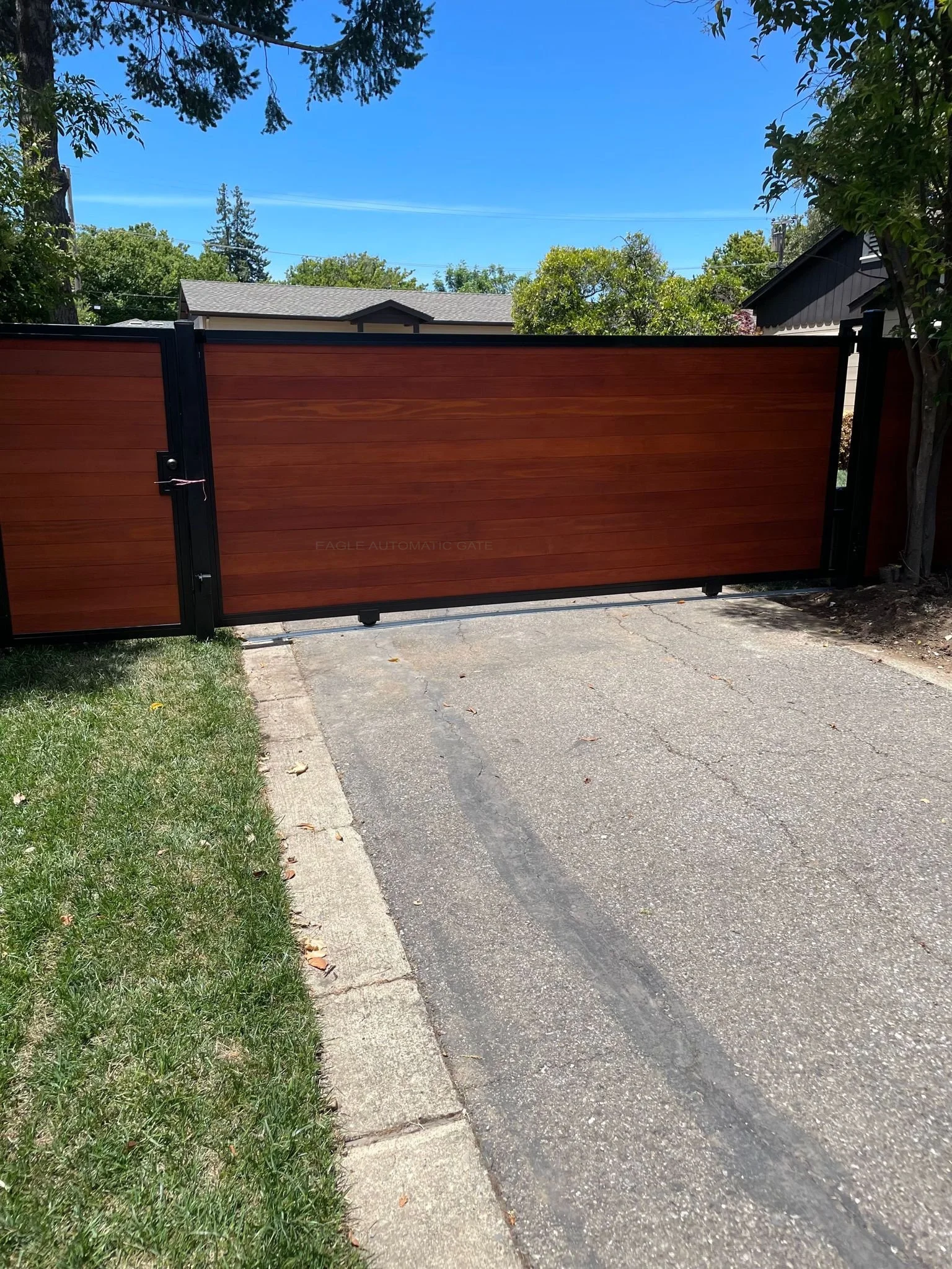 Redwood and black steel sliding driveway gate with a matching walk gate Redwood-infill driveway gate in a black steel frame