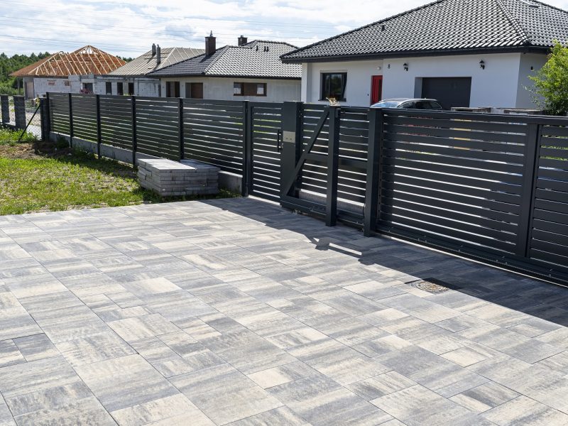 A modern panel fence in anthracite color, a visible sliding gate to the garage and a wicket with a letterbox. Slide Iron Gate