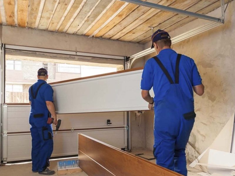 A modern panel fence in anthracite color, a visible sliding gate to the garage and a wicket with a letterbox.