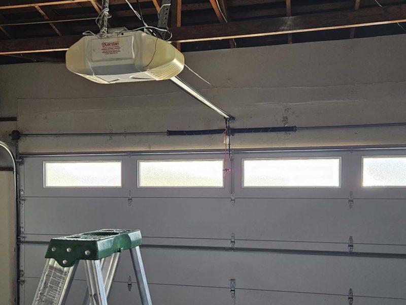 A modern panel fence in anthracite color, a visible sliding gate to the garage and a wicket with a letterbox.